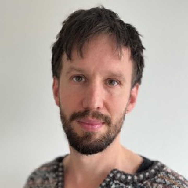 Ljushyad man med kort cendréfärgat hår i medelåldern, klädd i en stickad tröja.